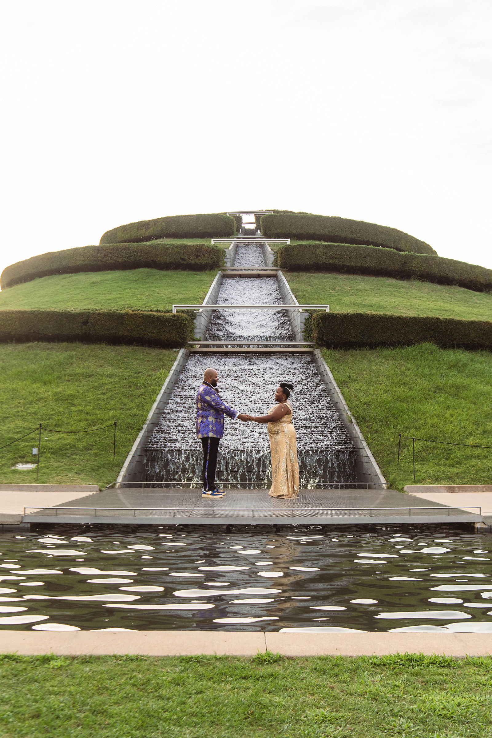 A wedding couple pose outside in front of a fountain in Houston Texas
